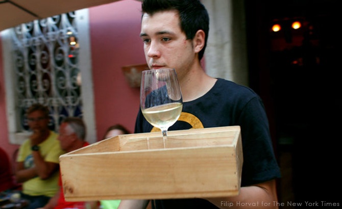 A waiter carries a glass of malvasia wine at a bar in Rovinj